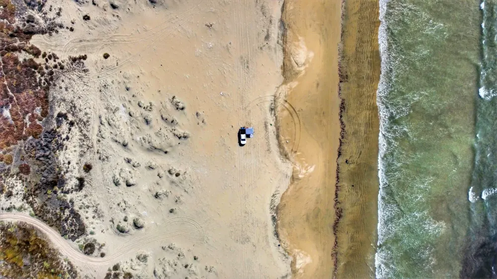 Vista aérea de la costa con un vehículo acampando
